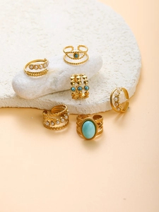 Set of six gold stainless steel rings featuring turquoise and white pearls on white stone