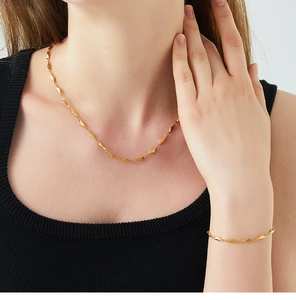 Close-up of geometric diamond fishbone necklace and bracelet set in 18K gold plated steel