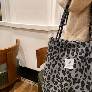 Detail view of leopard print corduroy tote bag with vintage label on a shoulder strap