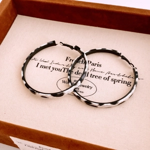 Detail view of large hoop earrings with black and white leopard pattern on velvet display