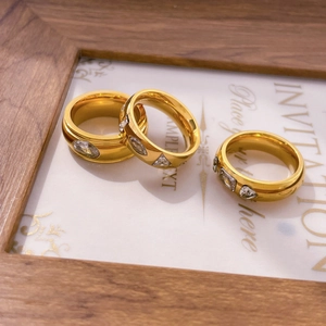 Three gold geometric rings with oval, triangle, and rectangle zircon on a white card