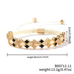 Detail shot of golden clover bracelet with black enamel, white zircons and braided rope