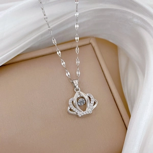 Macro shot of silver crown necklace with dancing stone on beige jewelry box with silk