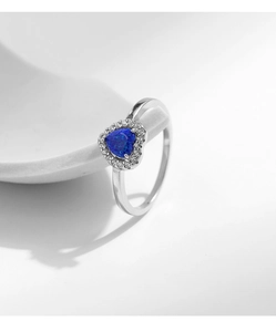 Detailed view of silver heart ring featuring a central blue gemstone and halo of zircons