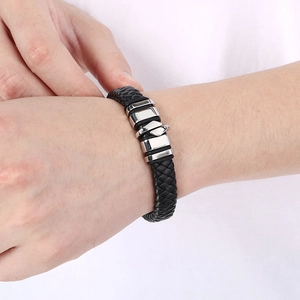 Dettaglio di bracciale da uomo in pelle intrecciata con chiusura magnetica in acciaio