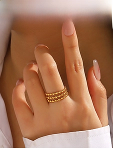 Détail d'une bague à triple rangée de perles dorées montrant son design minimaliste empilé