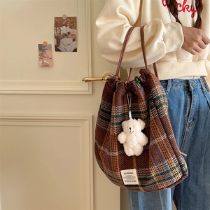Detail view of brown plaid woolen drawstring bag with cute plush bear keychain charm