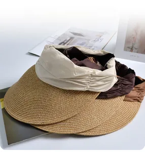 Detail view of woven straw sun visors in beige and coffee brown with pleated fabric bands
