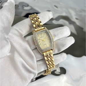 Macro view of tonneau emerald quartz watch with crystal bezel and gold mesh band