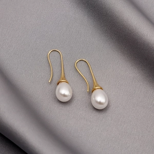 Classic vintage gold water drop pearl earrings displayed on elegant grey silk fabric