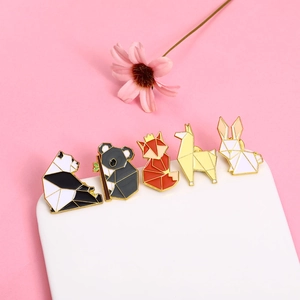 Close-up of geometric animal enamel pins including panda, koala, and fox on pink background