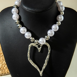Detail of multi-layer pearl necklace with large silver textured heart pendant on mannequin