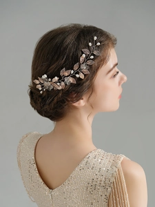 Close-up of bridal hair comb with golden leaves, white pearls and transparent flowers