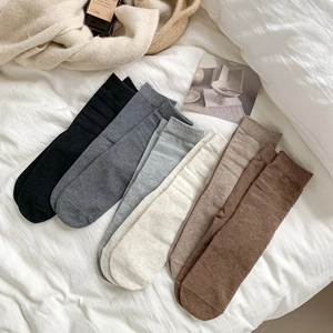 Maillard style cotton mid-calf socks in various brown tones on a soft white bed sheet