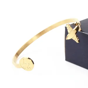 Gold stainless steel cuff bracelet with airplane charm and circular world map design