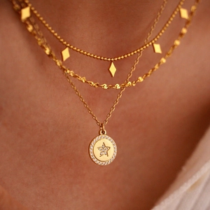 Layered gold necklace featuring a star pendant and sparkling rhinestones on a model