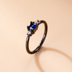 Detailed close-up of a black nose ring featuring an oval blue gem and micro-pave zircons