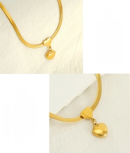 Detail of gold heart pendants on a sleek stainless steel snake chain with mirror finish