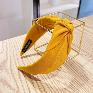 Detail of yellow fabric top knot headband with handmade label on wooden surface