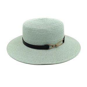 Detailed weave texture of mint green flat top straw hat with black band and gold buckle