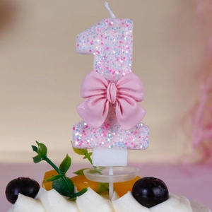 Close-up of pink number 1 glitter birthday candle with a cute decorative bow