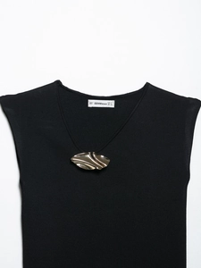 Detail of black knit sleeveless top with V-neckline and wavy golden metal accessory