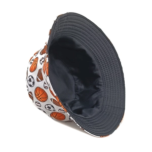 Reversible bucket hat with sports ball patterns like basketball and soccer on black fabric