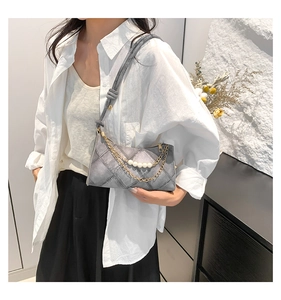 Détail du sac croissant en jean gris avec chaîne dorée et perles sur chemise blanche