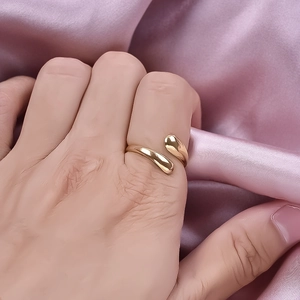 Minimalist 304 stainless steel open ring in gold finish worn on hand over silk background