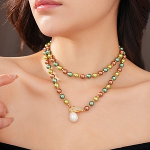 Dettaglio di una collana di perle a doppio strato con pendente a foglia d'oro e perla