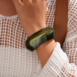 Detail of wide acrylic cuff bracelet with green marble texture on a model wrist