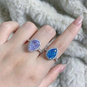 Close-up of pear-shaped purple and blue zircon rings on silver bands with small diamonds