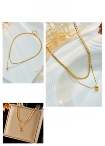 Close-up of double-layered gold bead pendant necklace on textured jewelry trays