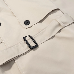 Gros plan du trench-coat beige avec boucle en résine noire et boutons détaillés