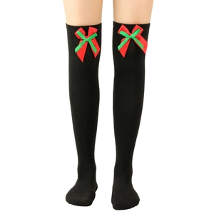Detail of black over-the-knee socks with red and green Christmas ribbon bows