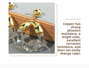 Macro detail of polished gold copper earring with transparent acrylic twisted hoop
