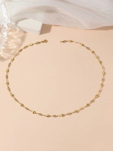 Detailed view of golden heart and oval link necklace on elegant white fabric background