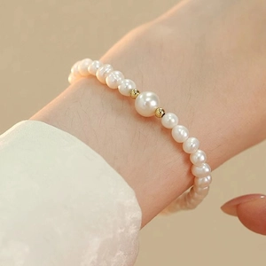 Detailed macro view of white freshwater pearls and gold beads on a delicate bracelet
