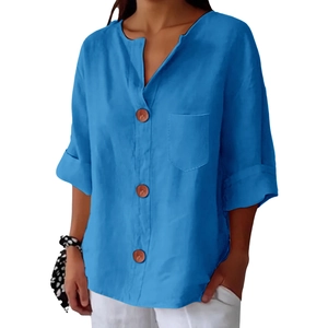 Dettaglio camicia blu in lino con scollo a V, bottoni in legno e tasca frontale