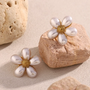 Macro shot of 18K gold plated flower earrings with faux pearls on natural stone base