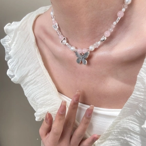 Detail of Y2K vintage butterfly pendant necklace with pearls and pink beads on a model