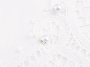 Détail macro du tissu en dentelle blanche avec boutons de perles élégants cousus