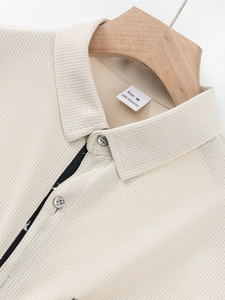 Close-up of beige waffle knit men's shirt collar and shoulder with 100% polyester label