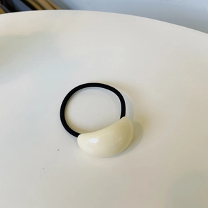 Minimalist elastic hair tie with cream-colored oval accent on white background