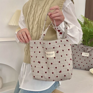 Détail du sac à déjeuner en toile avec pois rouges, motifs de nœuds et étiquette tissée