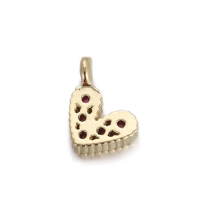 Detail of a heart-shaped gold pendant with red stones and a hollowed back grid
