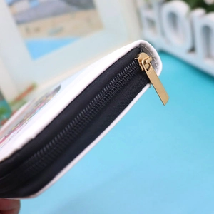 Close-up of white owl coin purse featuring a black zipper with a golden metal puller