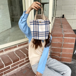 Plaid wool felt handbag held by a woman sitting on brick steps in a street setting
