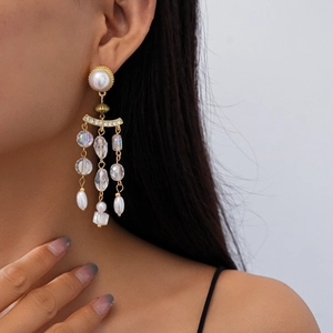 Detail view of pearl and crystal tassel earring on model in vintage golden finish