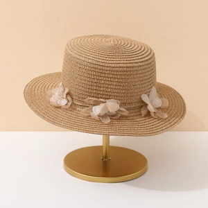 Elegant wide brim straw sun hat with mesh flower accents on a gold display stand